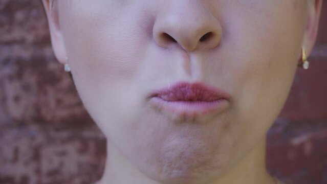 Young woman chews gum and blowing bubblegum bubble. Closeup view. 