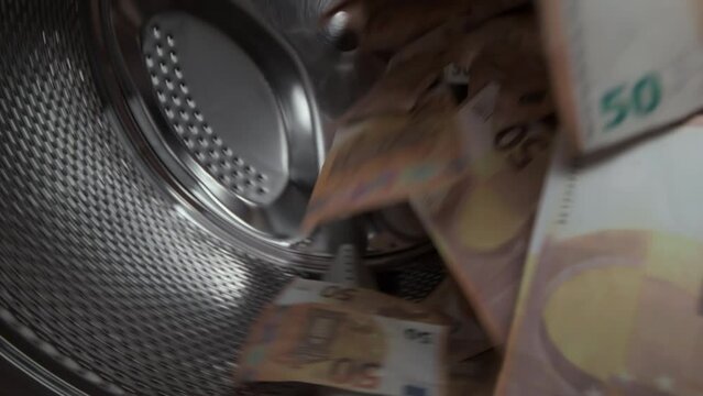 Washing a heap of fifty euro bills in washing machine, inside view of drum during spin cycle. Concept of money laundering, financial fraud.