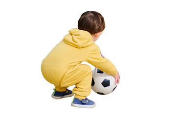 A toddler baby is kicking a football on the green grass in the park, isolated on white background. Kid aged two years (two-year-old boy)