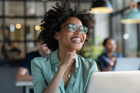 A euphoric businesswoman displays a big smile in the office boardroom, her laptop serving as a valuable tool for productivity.