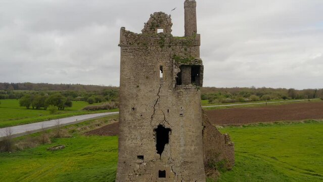 Aerial pullback captures Srah Tower in Tullamore, showcasing surrounding fields and canal. Symmetrical composition.