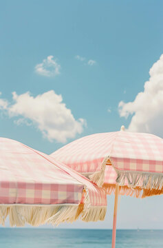Two beach pink and white umbrellas on the beach with sky above. Pastel colors, minimal aesthetic. Summer idea.