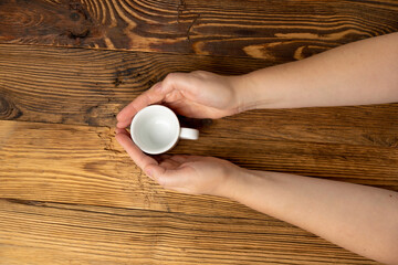 Hand Holds Cup, Empty White Cup in Hands, Coffee Mug, Teacup Mockup, Cup in Arms on Wooden Table