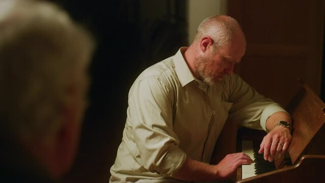 Sad man plays piano key in front of someone.