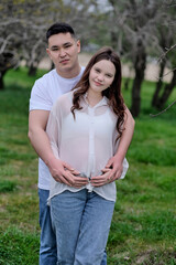 A photoshoot of a young interracial couple with a pregnant wife in nature