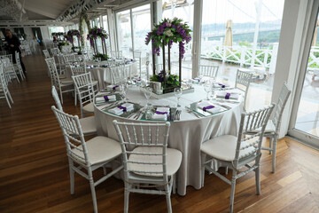The elegant wedding table ready for guests. Decorated white wedding table for a festive dinner with...