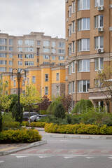 Fototapeta na wymiar Sofiivska Borshchahivka, Ukraine. April 16, 2024 Good variety of houses in residential complex. gray cloudy sky and flowering trees in the area. many cars are parked and people are walking.