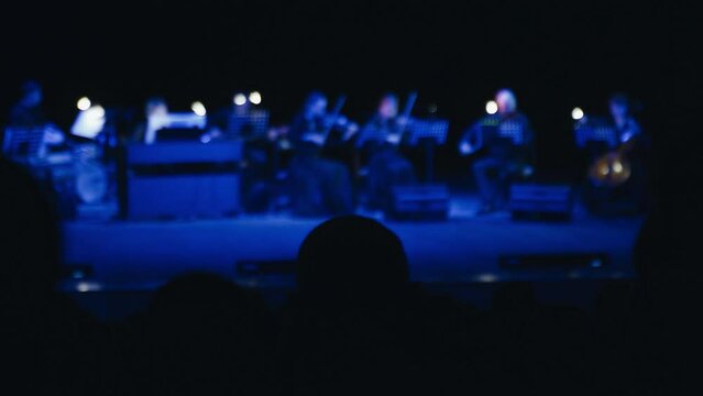 Silhouettes of people in the audience listening to a classical music concert.