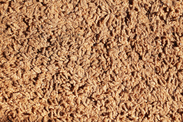 Brown carpet texture. Closeup fiber background. Soft plush fabric pattern. Furry rug background. Grainy noise design. Textile background.