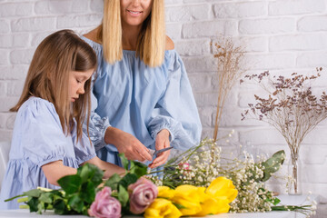Florist shop little family business. Daughter helps mother making flower bouquets 