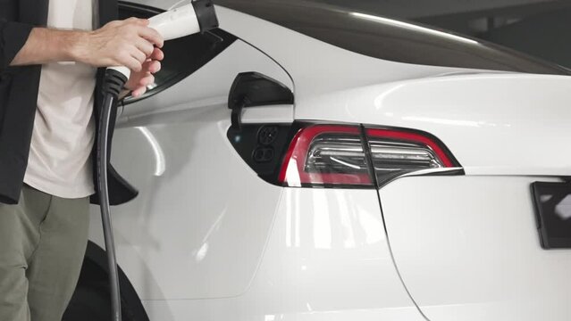 Slow motion couple travel with EV electric car to shopping center parking lot charging in downtown city as urban sustainability lifestyle by green clean rechargeable energy of electric vehicle innards