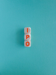 Concept red word IPO on wooden cubes. Beautiful blue background. Business and IPO concept.