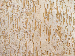 Peeling Beige Paint on a Rough Wall Texture. Weathered wall with flaking paint exhibiting aging