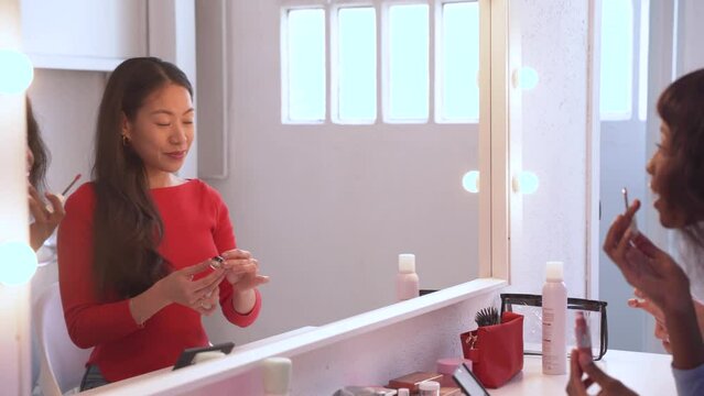Young female friends putting on some professional makeup in dressing room. High quality 4k footage