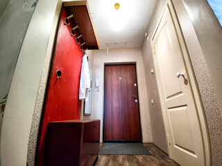 Spacious Hallway With Red Accent Wall, Wooden Doors, and Laminate Flooring. The hallway of an old...