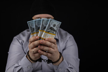 A man holds in his hands a large amount of money for which he was arrested. A man in a balaclava...