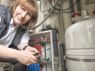Female middle aged Technician Adjusting Industrial Water Filtration System. A woman services a...