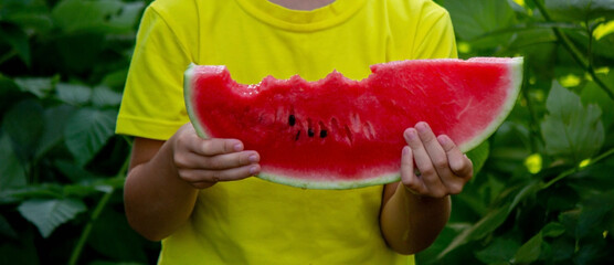 a boy eats a delicious piece of watermelon in the summer.