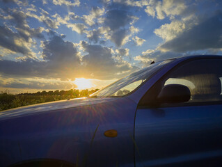 car at sunset, blue car in nature at sunset in the rays of the sun