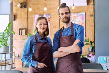 Business team, confident colleagues young man and woman in aprons at workplace