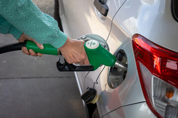 Filling up with expensive gasoline mixed with bio ethanol at a gas station with a filling nozzle in...
