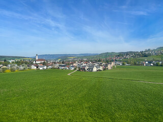 Fototapeta na wymiar A scenery of of countryside nature of Switzerland and bleu sky, cloud with green grass trees and nature with houses of the village during sunny spring season 