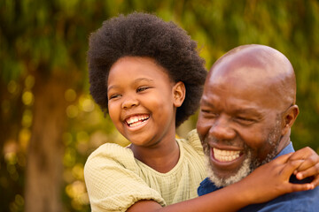 Close Up Of Loving Grandfather Laughing And Hugging Granddaughter Outdoors In Countryside Or Garden