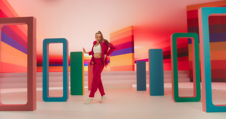 Professional Female Performer Energetically Rehearsing a Modern Dance Choreography in a Colorful Studio. Stylish Woman Looking at the Camera and Dancing Expressively, Practicing Her Routine.