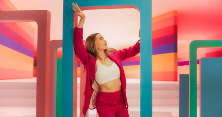 Portrait of Talented Energetic Woman Dancing with Hypnotic Hand Movement While Looking at the Camera: Stylish Female Dancer Performing a Modern Choreography in Studio with Colorful Funky Background