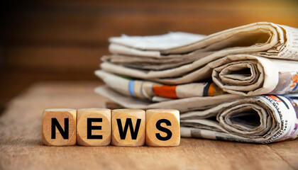 Stacked and folded newspapers, above the word NEWS in wooden block puzzle dice, on a wooden table or desk. concept for newspaper, the media, press release and global communications. Generative Ai.