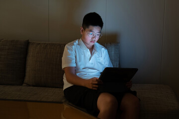 Teenager using digital tablet at night