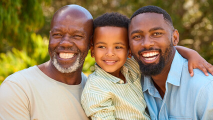 Portrait Of Loving Three Generation Male Family Laughing And Hugging Outdoors In Countryside