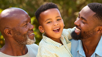 Loving Three Generation Male Family Laughing And Hugging Outdoors In Countryside