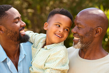 Loving Three Generation Male Family Laughing And Hugging Outdoors In Countryside