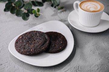 Fresh coffee and chocolate cookies on textured background