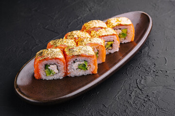 Luxury gold leaf sushi rolls on dark plate