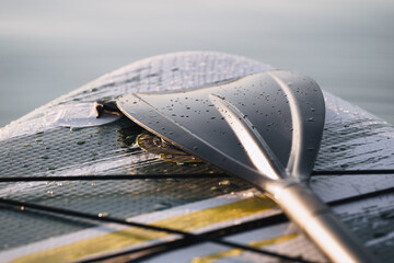 Close up of a Stand Up Paddle surf board or SUP on the lake with water drops. Gray background.