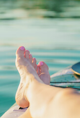 Close-up of a woman's well-groomed, polished foot on a paddleboard in summertime on the water. Relaxing. Enjoying the vacation.