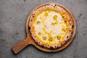 Italian cheese pizza with pickles on wooden board