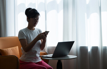 Woman using phone and laptop on coffee table