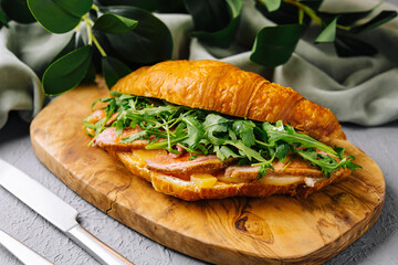 Gourmet croissant sandwich with bacon and arugula
