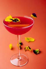 Elegant cocktail with edible flowers on warm background