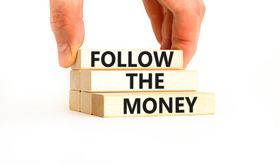 Follow the money symbol. Concept words Follow the money on beautiful wooden blocks. Beautiful white table white background. Businessman hand. Business and follow the money concept. Copy space.