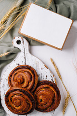 Rustic cinnamon rolls and blank card on wooden board
