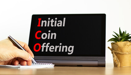 ICO initial coin offering symbol. Concept words ICO initial coin offering on beautiful black tablet. Beautiful white background. Businessman hand. Business ICO initial coin offering concept Copy space