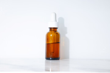 A display of a small and brown beauty serum in a white background