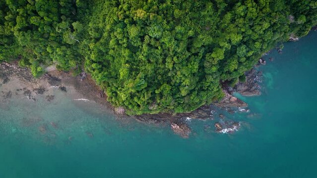 Lush green trees blanket the mountainside bathed in the soft light of a summer morning at Phayam Island in Ranong, Thailand