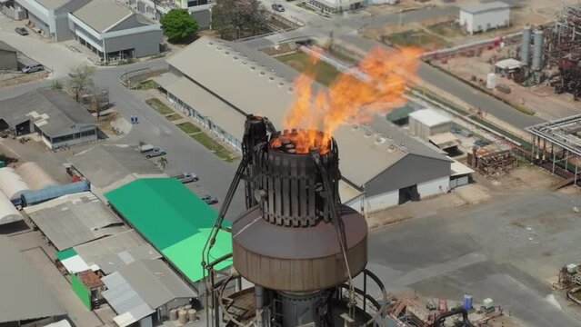 Aerial view of fire explode at the end of chimney for combustion excess gas before release into the air in the chemical oil refinery plant, 4k video