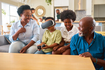 Grandparents With Grandchildren Wearing Virtual Reality Headset Playing Game At Home Together - obrazy, fototapety, plakaty