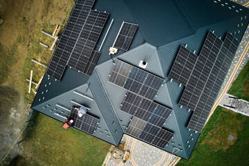 Roofers building photovoltaic solar module station on roof of house. Men electricians in helmets...
